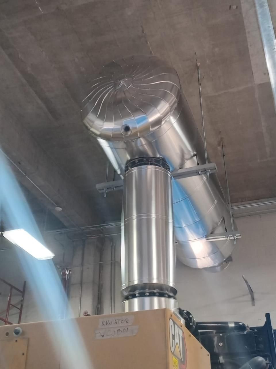 Sistema de ductos industriales de ventilación en acero galvanizado instalados en techo de nave industrial, conectados a maquinaria Caterpillar